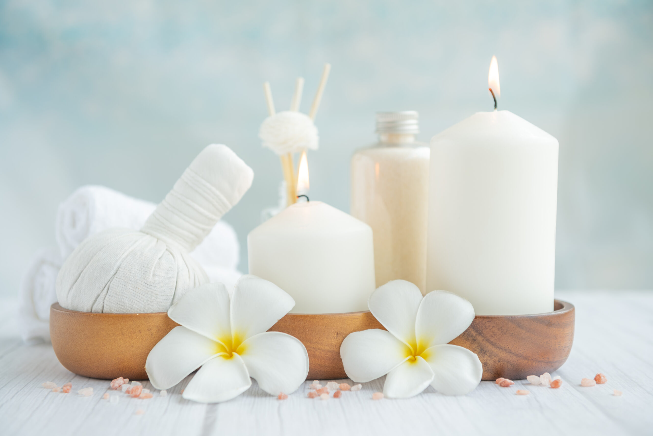 Natural relaxing spa composition on massage table in wellness center    with towels, flowers and salt, candle  on massage table in spa salon.
